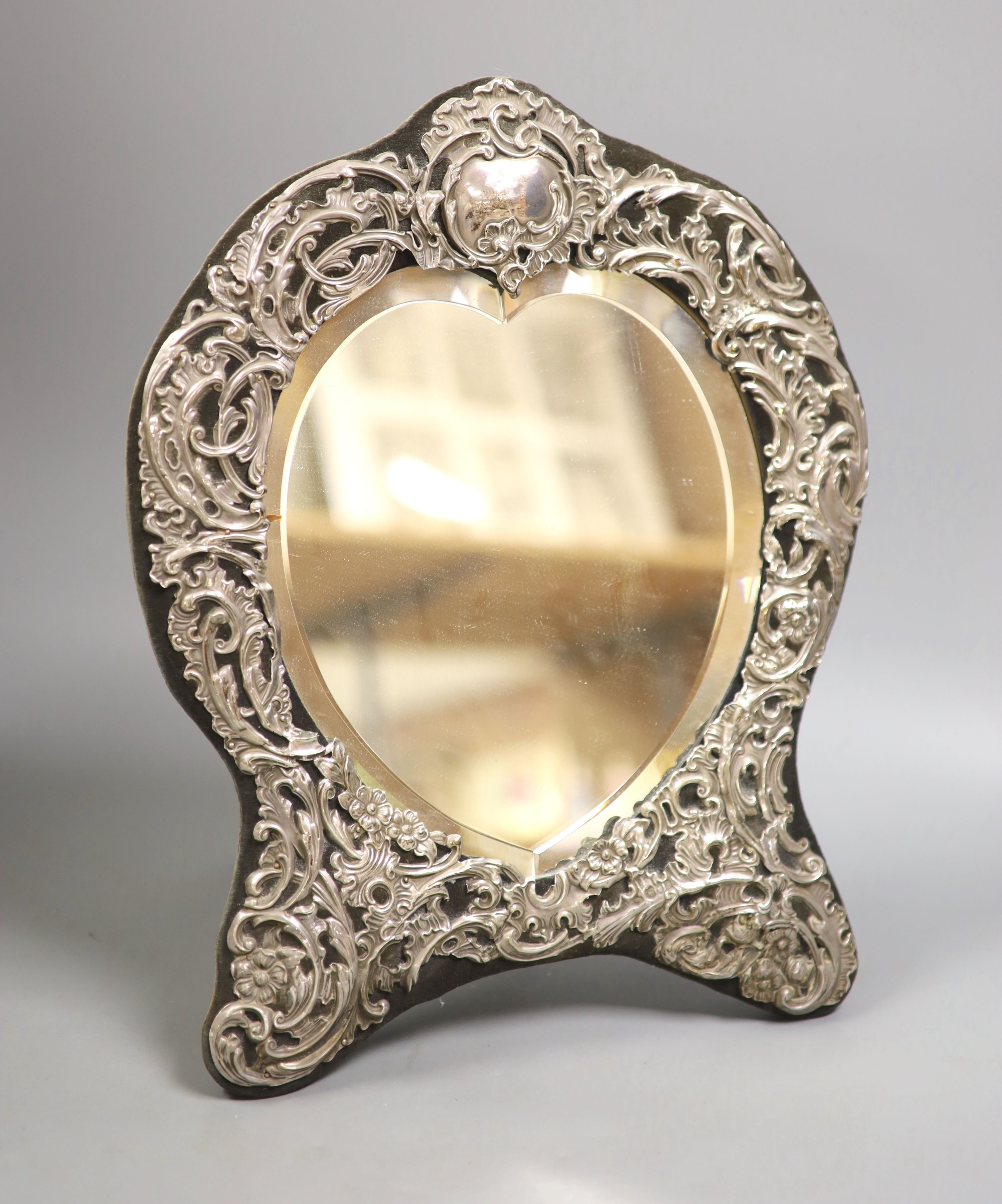 An Edwardian repousse silver mounted easel mirror, with heart shaped plate, William Comyns, London, 1906, 36cm.